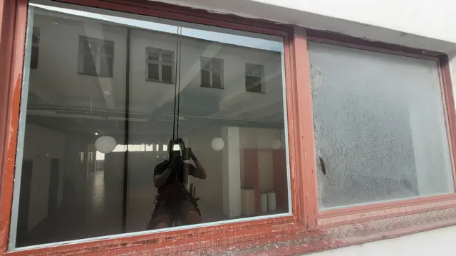 Výškový pracovník provádí postavební mytí oken pomocí lanového přístupu