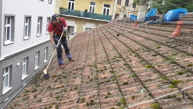 Výškový pracovník čistí střechu rodinného domu